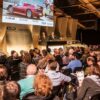 Crowd of people bidding on Porsches at auction