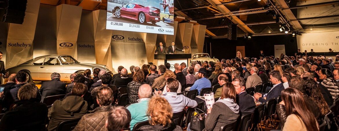 Crowd of people bidding on Porsches at auction