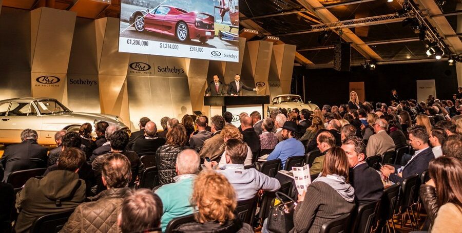 Crowd of people bidding on Porsches at auction