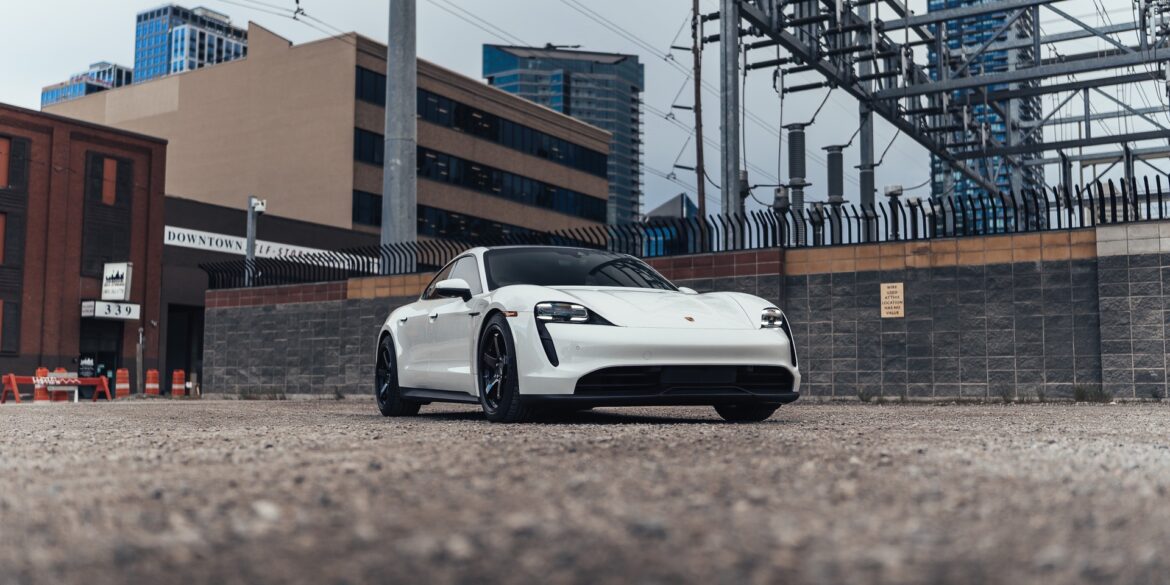 White Porsche Taycan electric car in industrial area